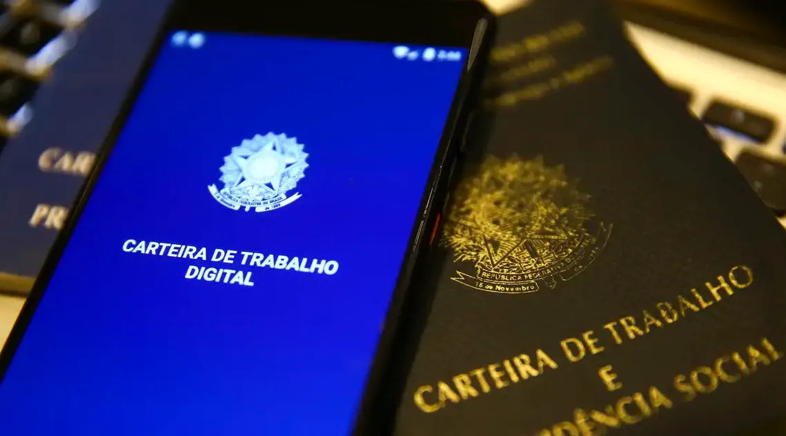 Tela de smartphone exibindo carteira de trabalho digital ao lado de carteira de trabalho física, representando consulta de FGTS.