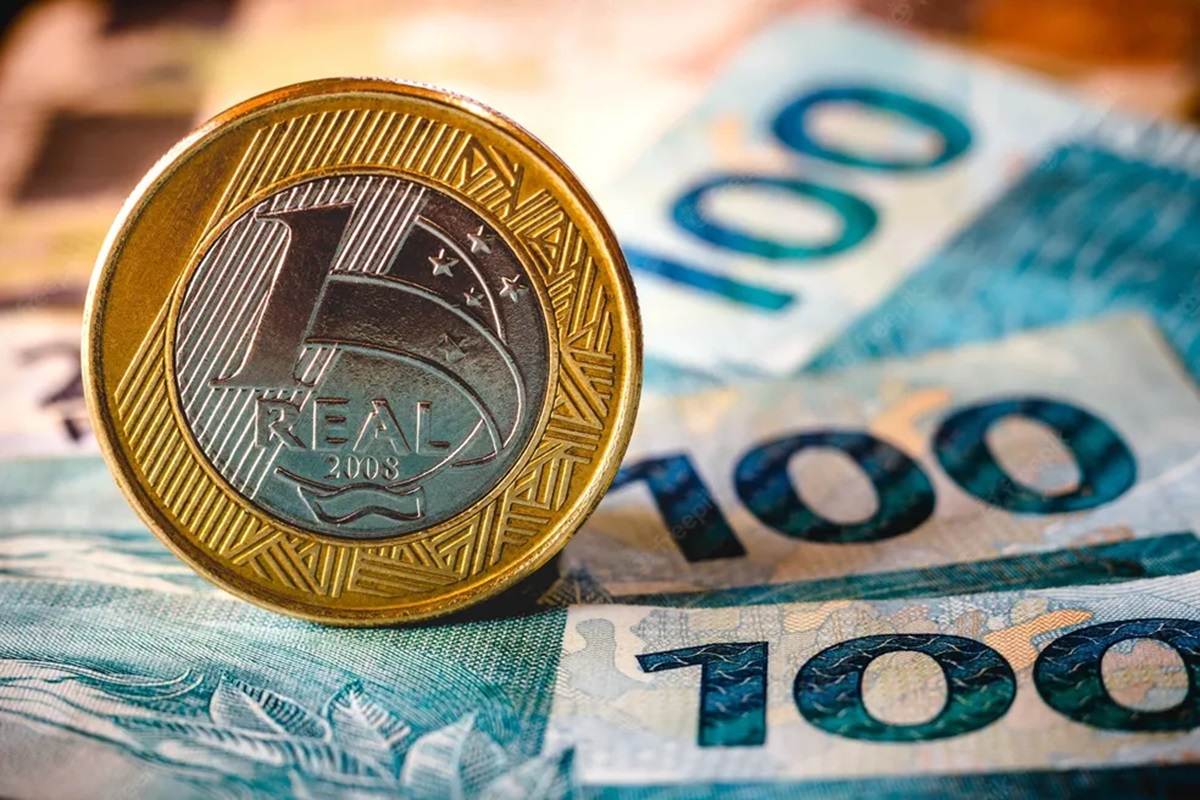 Moeda de R$ 1 com notas de R$ 100 ao fundo, simbolizando o dinheiro esquecido no Banco Central.