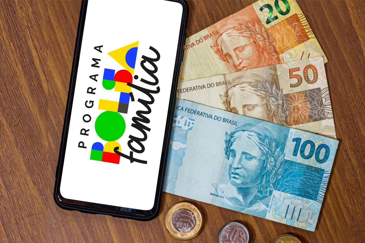Celular exibindo o logo do Bolsa Família ao lado de cédulas e moedas do Brasil.