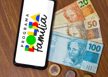 Celular exibindo o logo do Programa Bolsa Família junto a cédulas de R$20, R$50 e R$100.