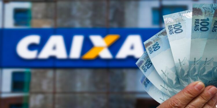 Notas de 100 reais sendo exibidas em frente à fachada da Caixa Econômica Federal