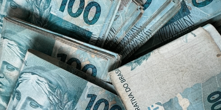 Notas de 100 reais brasileiras representando o tema de como gerenciar finanças e controlar empréstimos pessoais.