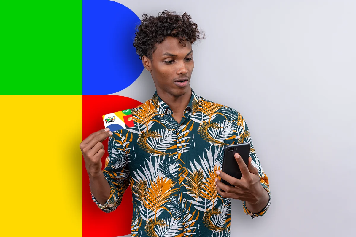 Homem segurando cartão do Bolsa Família enquanto consulta o aplicativo no celular