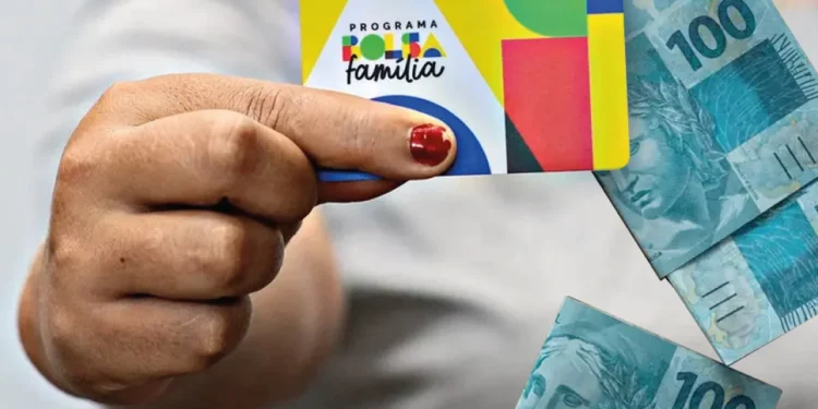 Cartão do programa Bolsa Família com cédulas de 100 reais ao fundo. Imagem ilustrativa do benefício social no Brasil.