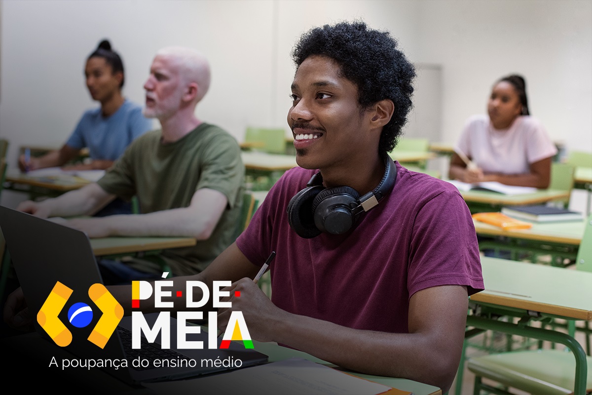 Estudante sorrindo enquanto usa um laptop em uma sala de aula, com outros colegas ao fundo. O logo do programa 'Pé-de-Meia' aparece na parte inferior da imagem.