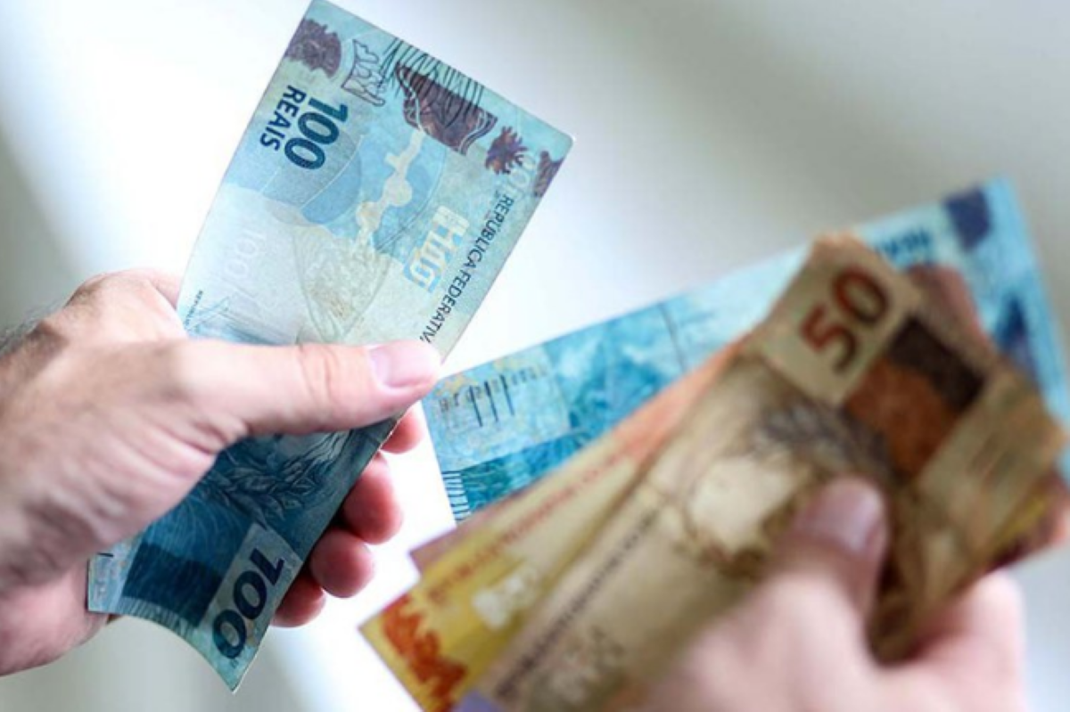 Notas de dinheiro, incluindo R$100 e R$50, representando uma transação de crédito pessoal.