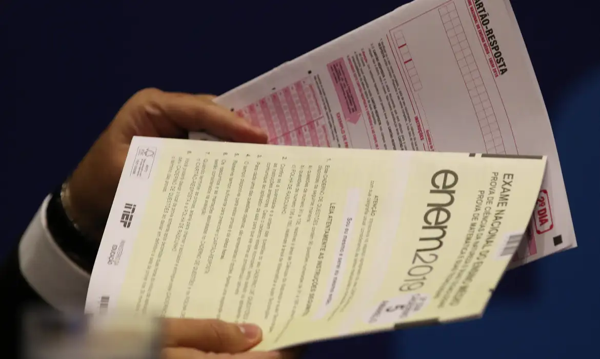 Prova do Enem sendo segurada por candidato, destacando a importância da nota mínima exigida