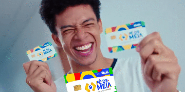Pessoa sorrindo enquanto segura os cartões do programa Pé-de-Meia