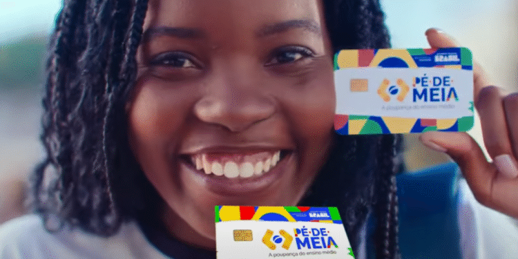 Jovem sorrindo com um cartão do programa Pé-de-Meia, que oferece até R$ 9.200 para jovens de 14 a 24 anos garantirem seu estudo.