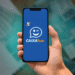 Como consultar meu saldo do Caixa Tem pelo CPF? 13 Imagem do aplicativo Caixa Tem em um smartphone, com logo visível em fundo azul e cédulas de dinheiro ao fundo.