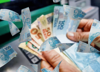 Pessoa segurando cédulas de 50 e 100 reais com notas de R$ 100 flutuando no ar, simbolizando pagamento via PIX.