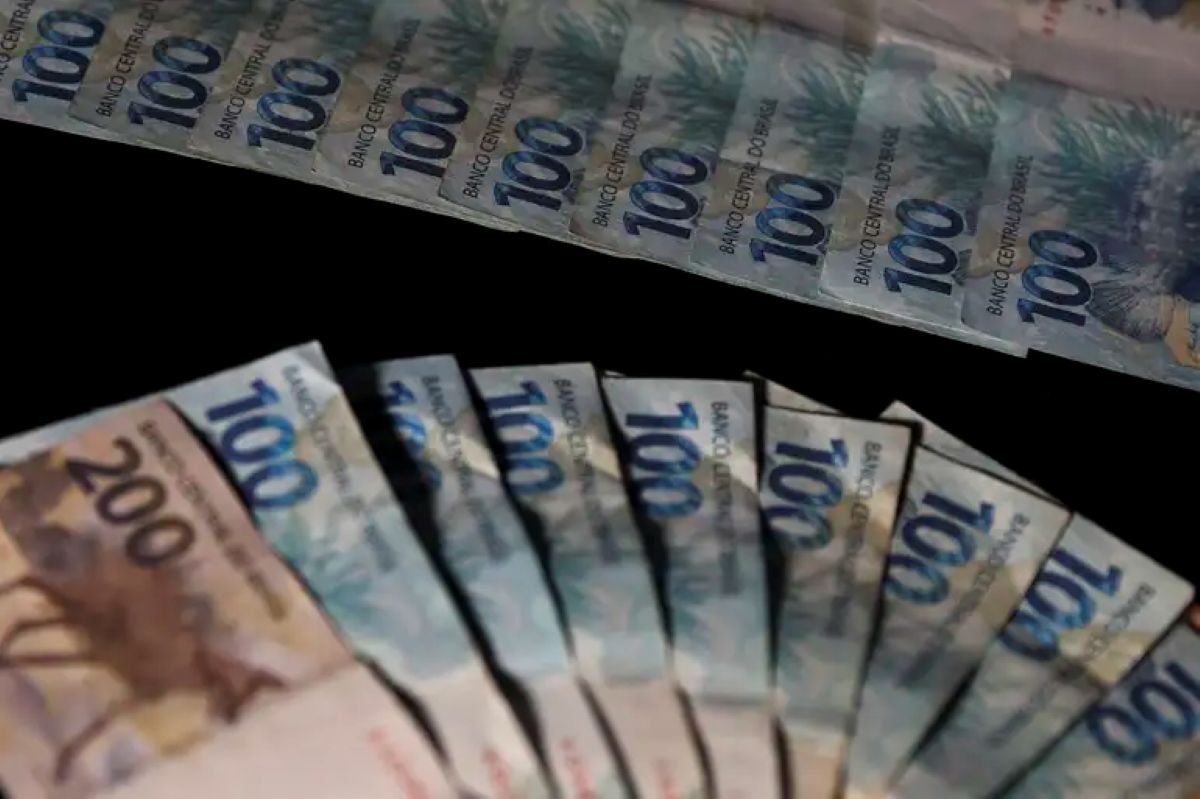 Pessoa contando notas de 100 reais em pagamento de valores atrasados