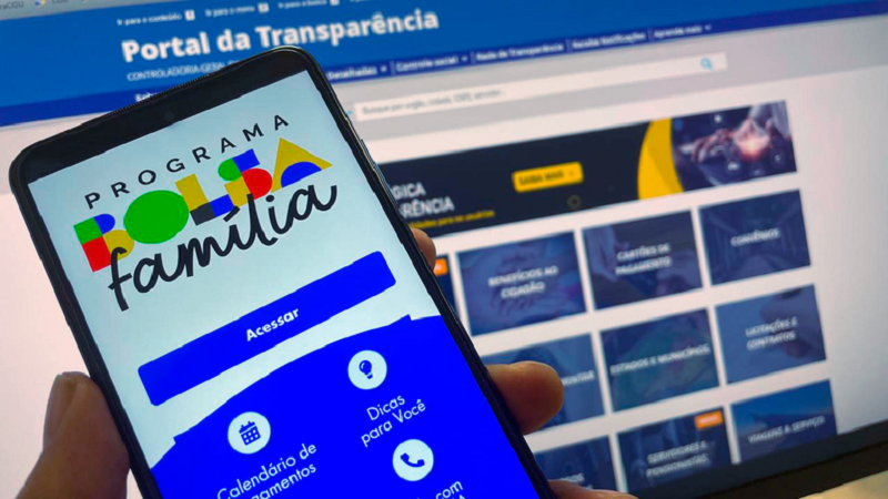 Imagem ilustrativa do programa Bolsa Família, com o logo do programa na tela de um smartphone, enquanto ao fundo aparece o portal da transparência do governo.