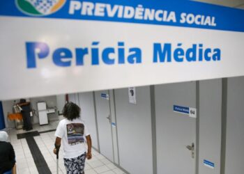 Pessoa caminha em corredor de agência da Previdência Social- INSS para realizar perícia médica
