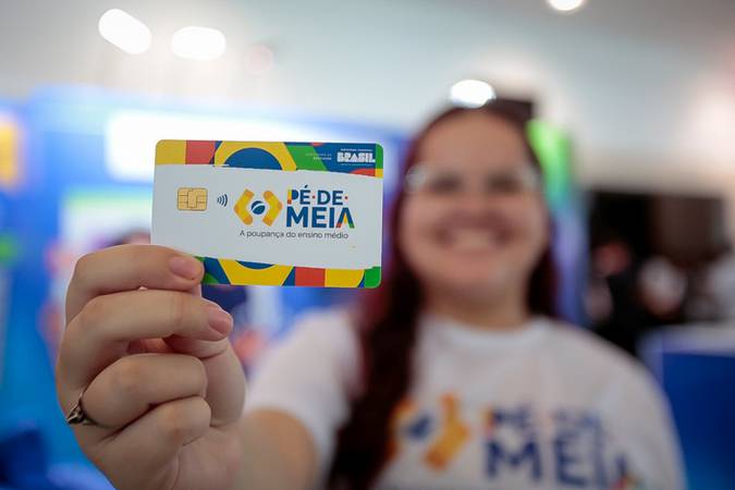 Pessoa segurando o cartão do programa Pé-de-Meia, um incentivo financeiro para estudantes do ensino médio.