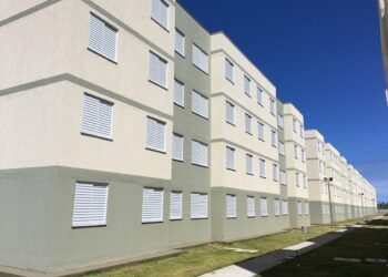 Prédios habitacionais do programa Minha Casa Minha Vida com céu azul ao fundo.