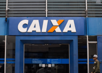 Agência da CAIXA Econômica Federal com pessoas caminhando em frente, referente ao pagamento do Bolsa Família.