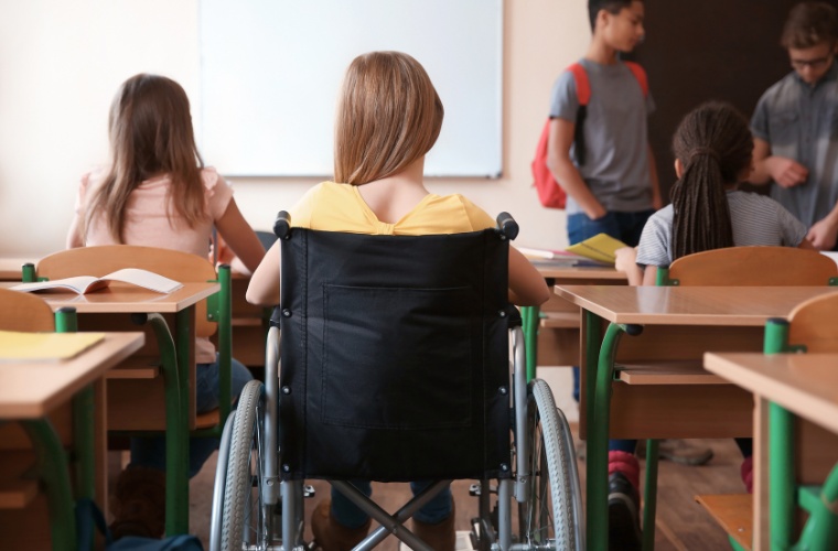 BPC na escola. Criança em cadeira de rodas na sala de aula, representando a inclusão de pessoas com deficiência no ambiente escolar.