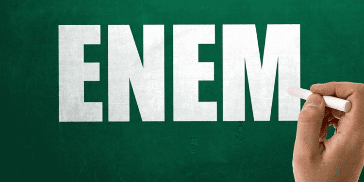 ENEM 2025! Como ganhar R$ 200 extras da participação no exame 1 Mão segurando giz escrevendo a palavra ENEM em um quadro verde.