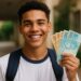 Jovem sorrindo e segurando notas de dinheiro brasileiro